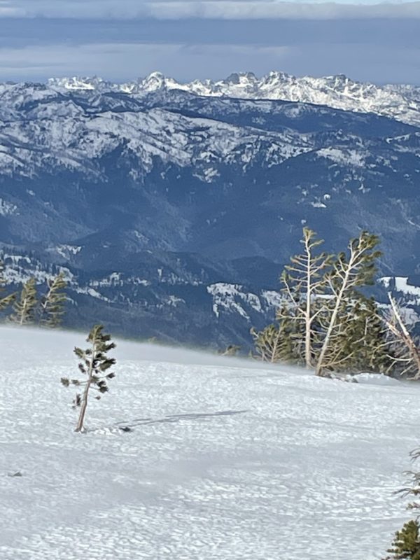Strong southern winds transporting loose snow into north aspects on top of granite mountain.